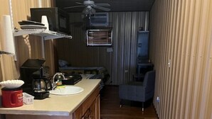 Une cuisine de taille réduite, dotée d’un plan de travail en bois, d’un ventilateur de plafond et d’un petit coin repas.