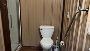 Une petite salle de bain comprenant des toilettes, un espace douche et un lavabo.