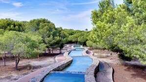 A natural pool with a stone pathway and lush greenery. - Tranquil 2-bedroom apartment with AC in La Mata (La Mata)