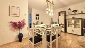 A dining area with a glass table, white chairs, and a vase of pink flowers. - Tranquil 2-bedroom apartment with AC in La Mata (La Mata)