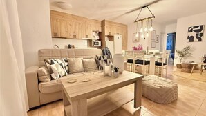 A modern living room with a sofa, a wooden dining table, and a kitchen area with wooden cabinets. - Tranquil 2-bedroom apartment with AC in La Mata (La Mata)
