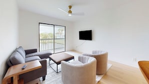 Una sala de estar moderna con un sofá, dos sillones, una mesa de centro y un televisor montado en la pared.