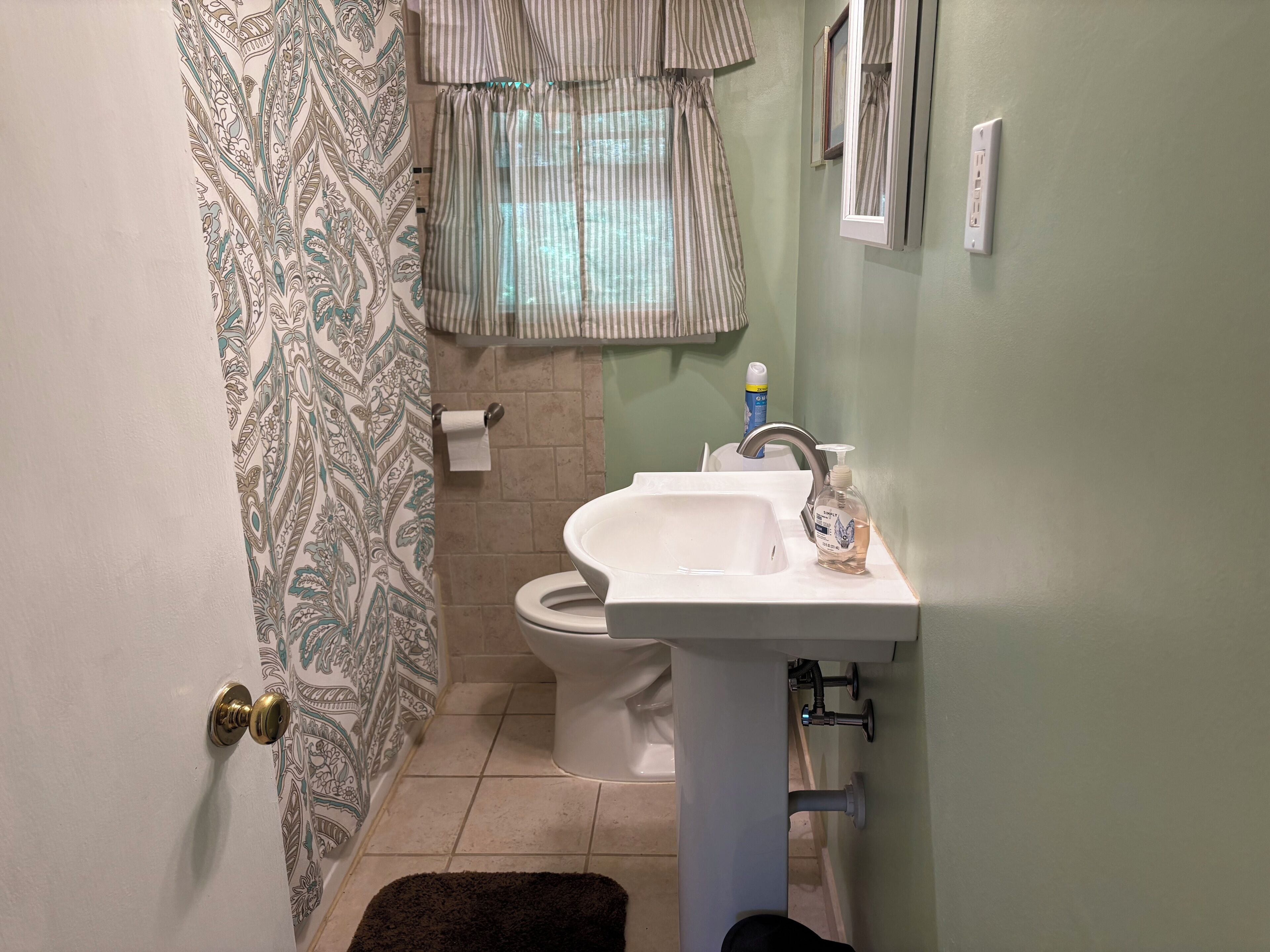 Une salle de bain avec des toilettes, un lavabo et un rideau de douche à motifs.