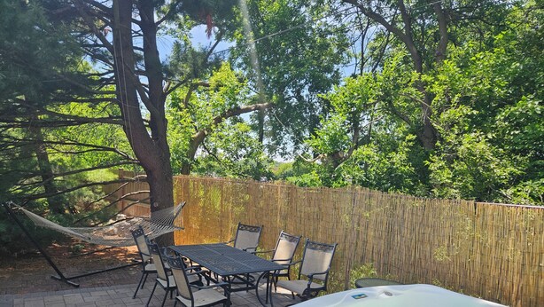 An outdoor patio with a hot tub, wicker chairs, and a table. - Hot Tub Retreats (Lake Villa)