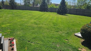 A well-maintained backyard with a wooden deck, a wooden fence, and a variety of plants and flowers. - Hot Tub Retreats (Lake Villa)