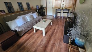 A living room with a sofa, coffee table, and a dining area with chairs and a table. - Hot Tub Retreats (Lake Villa)