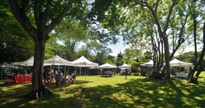 An outdoor market with white tents and tables set up on a grassy area surrounded by trees. - Villa in Sea Horse Ranch, Cabarete's Most Exclusive Oceanfront Gated Community! (Sosúa)