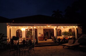 A building with a covered patio area, outdoor seating, and potted plants.