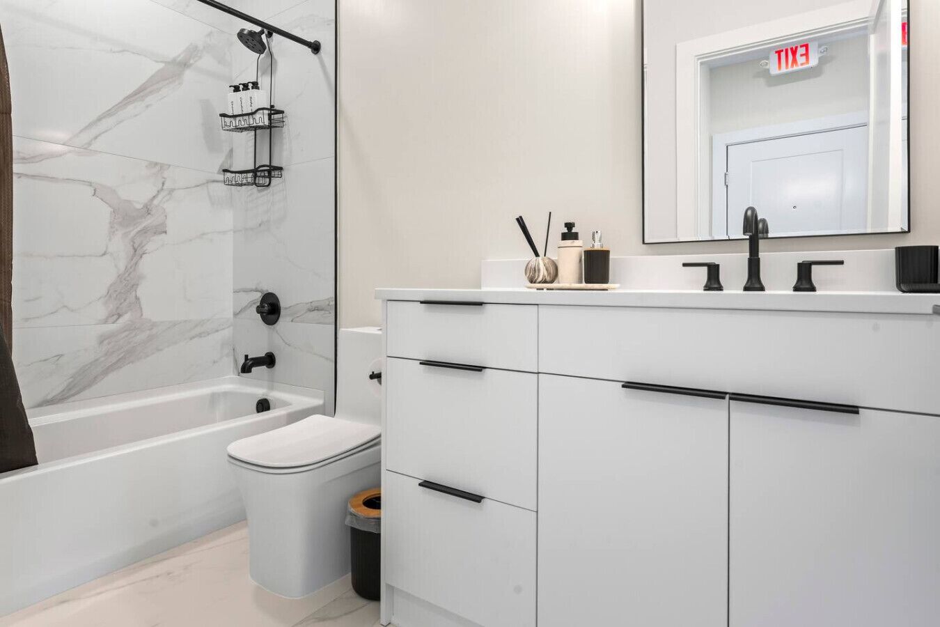A modern bathroom with a marble shower wall, a toilet, and a vanity with a mirror.