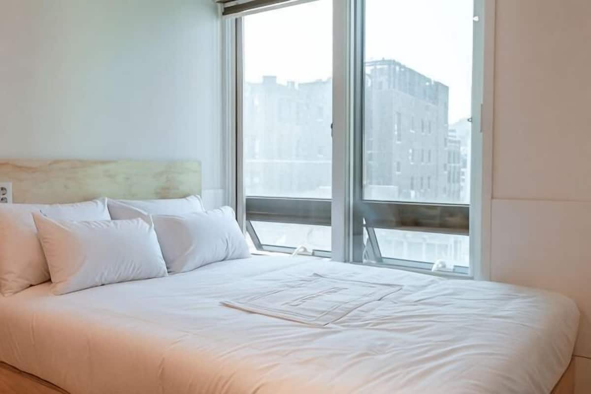A hotel room with a large bed, a window with a city view, and a headboard.