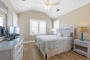 A bedroom with a bed, a television, a ceiling fan, and a window with blinds.