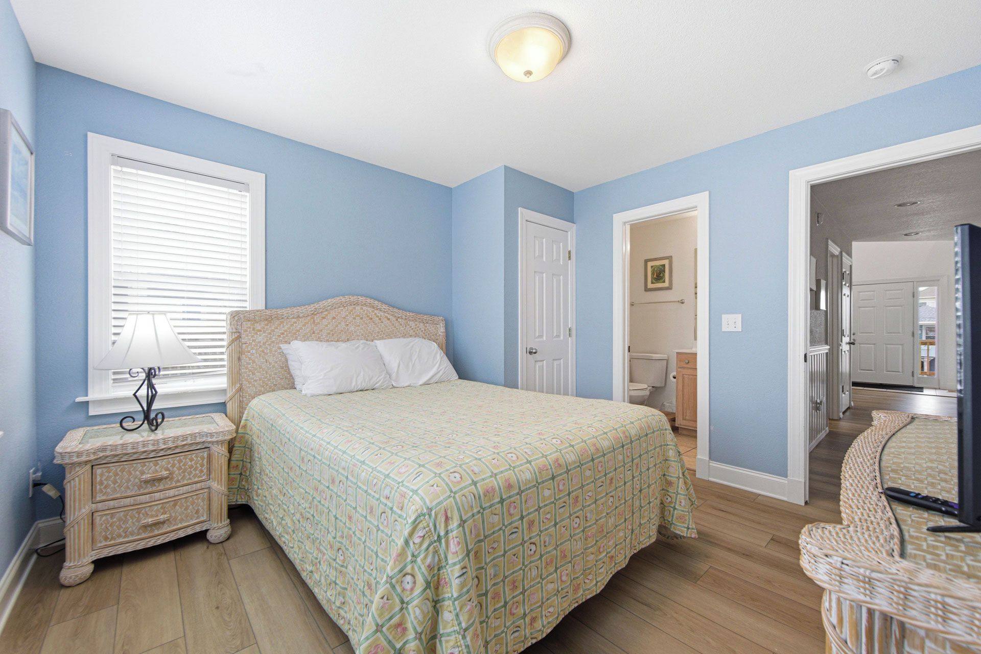 Un dormitorio con cama, mesita de noche, lámpara y una puerta que da al baño.