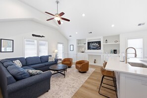 A modern living room with a sectional sofa, a coffee table, and a ceiling fan.