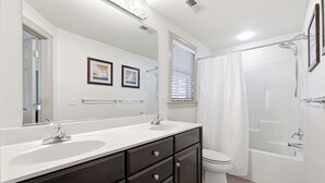 Un baño con dos lavamanos, inodoro, ducha y un espejo grande.