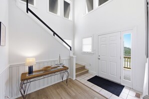 A staircase leading to a landing with a door and a view of the outdoors. - Sebastian by the Sea: Oceanside, Private Pool, Hot Tub, Foosball Table (Kill Devil Hills)