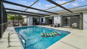 A covered outdoor swimming pool with a slide, lounge chairs, and a patio area. - Coastal Family Retreat – Heated Pool, Fire Pit & Fun! (Holiday)