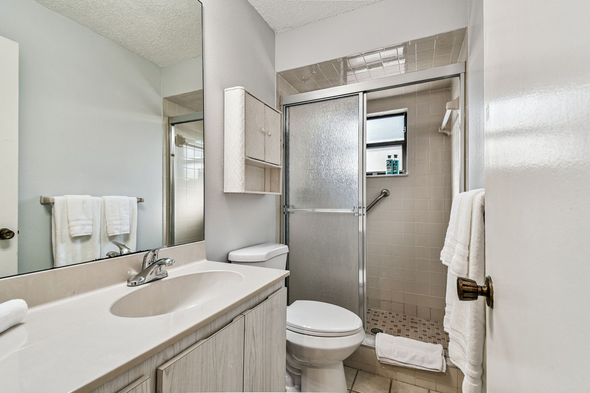 A bathroom with a sink, toilet, and a glass-enclosed shower area.