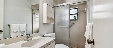 A bathroom with a sink, toilet, and a glass-enclosed shower area.