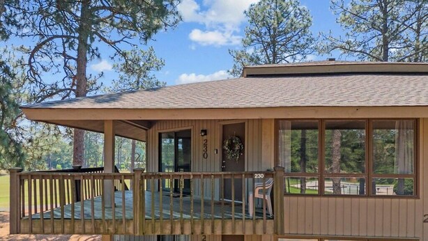 Une cabane à deux étages dotée d’une terrasse, de grandes fenêtres et offrant une vue sur la forêt environnante.