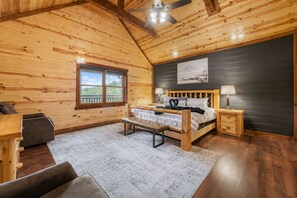 Een houten slaapkamer met een bed, een bankje, nachtkastjes en een raam met uitzicht.
