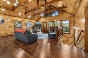A spacious log cabin interior with a fireplace, a sofa, and a dining area.