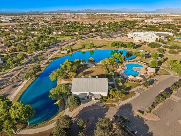 An aerial view of a residential area with multiple swimming pools, a large building, and surrounding greenery. - Heated Pool Oasis | Family Retreat in Gilbert (Gilbert)
