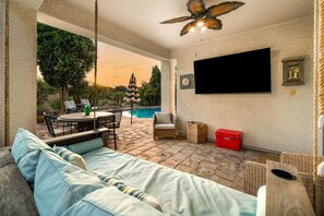 A sunlit patio with a pool, outdoor furniture, and a ceiling fan. - Heated Pool Oasis | Family Retreat in Gilbert (Gilbert)