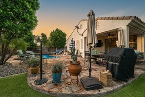 A patio with outdoor furniture, a barbecue grill, and a pool.