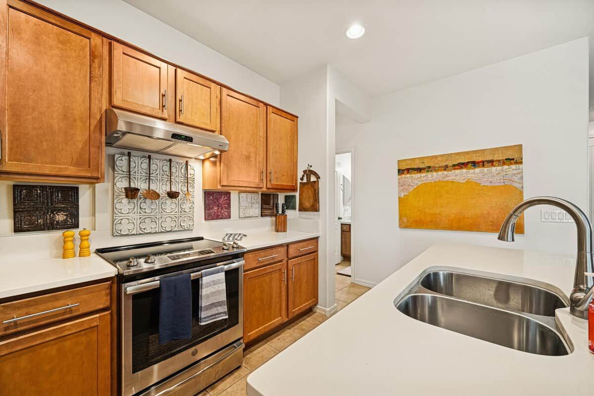 Cocina con armarios de madera, pileta de acero inoxidable y salpicadero de azulejos.