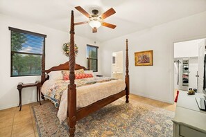 A four-poster bed with a ceiling fan, a patterned rug, and a wooden nightstand. - Heated Pool Oasis | Family Retreat in Gilbert (Gilbert)