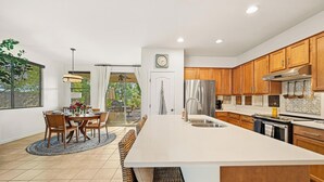 Una cocina moderna con armarios de madera, una isla grande y un comedor con mesa y sillas.