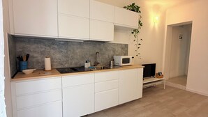 Una cocina moderna con armarios blancos, un salpicadero gris y un microondas.