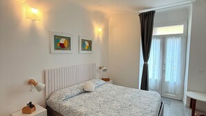 Un dormitorio con cama, mesitas de noche, lámparas de pared y obras de arte.