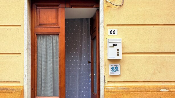 Una puerta de madera con una cortina, un buzón y el número 66 en la pared.
