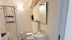 Un baño pequeño con lavadora, inodoro y lavabo.