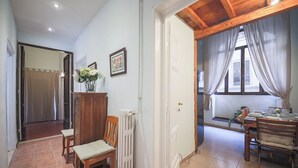 A dining area with a wooden table and chairs, a radiator, and a window with curtains.