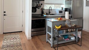 Una cocina moderna con vigas de madera en el techo, electrodomésticos de acero inoxidable y una pequeña mesa de comedor.