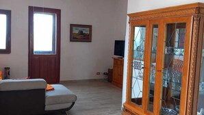Ein geräumiges Wohnzimmer mit Holzschrank, Sofa, Deckenventilator und Fernseher.