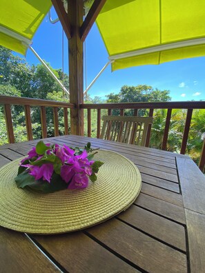 A wooden deck with a woven mat and a bouquet of purple flowers. - Zen bungalow with private Jacuzzi (Le Gosier)