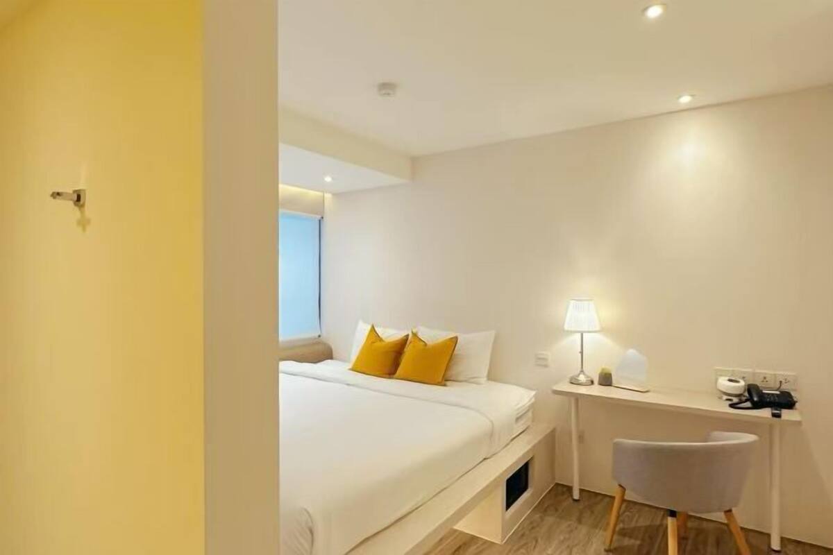 Ein Hotelzimmer mit einem Bett, einem Schreibtisch, einem Stuhl und einer Lampe.