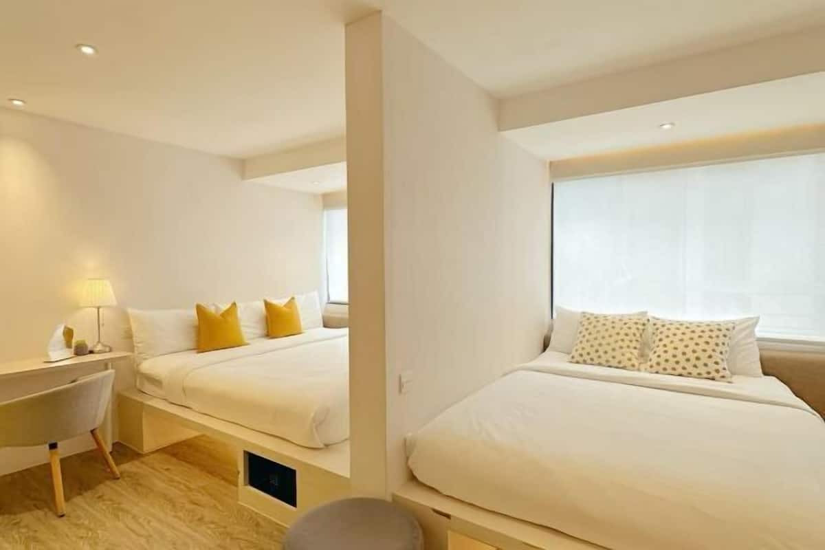 Ein Hotelzimmer mit zwei Betten, einem Schreibtisch und einem Stuhl.