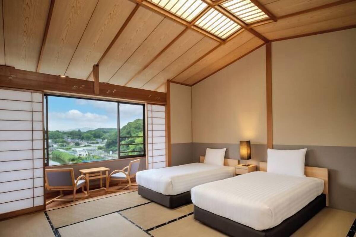 Un dormitorio con dos camas, vista a un paisaje y una zona de estar de estilo tradicional japonés.