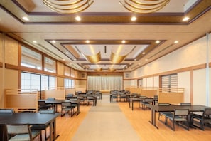 A conference room with multiple tables and chairs, large windows, and a ceiling with recessed lighting.