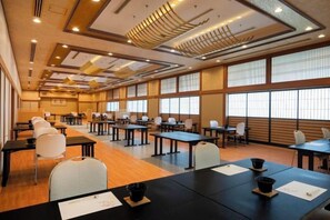 Une salle de conférence dotée de plusieurs tables et chaises, de grandes fenêtres et d’un plafond au design original.