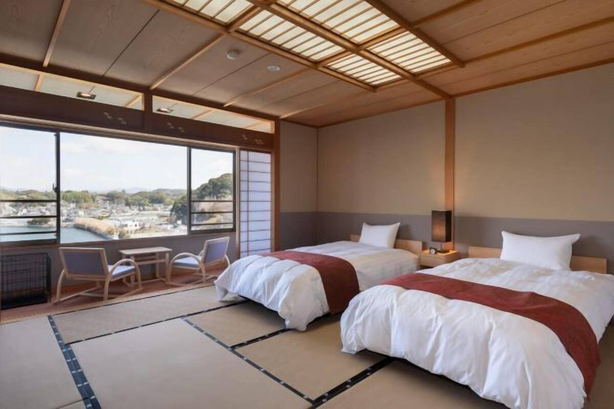 Habitación de hotel con dos camas, vista a la ciudad y techo de estilo japonés tradicional.