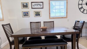 A dining room with a wooden table and chairs, framed pictures on the wall, and a clock. - Pet-Friendly Mountain Studio - Cozy Stay with Patio & Covered Private Parking (Kingsport)