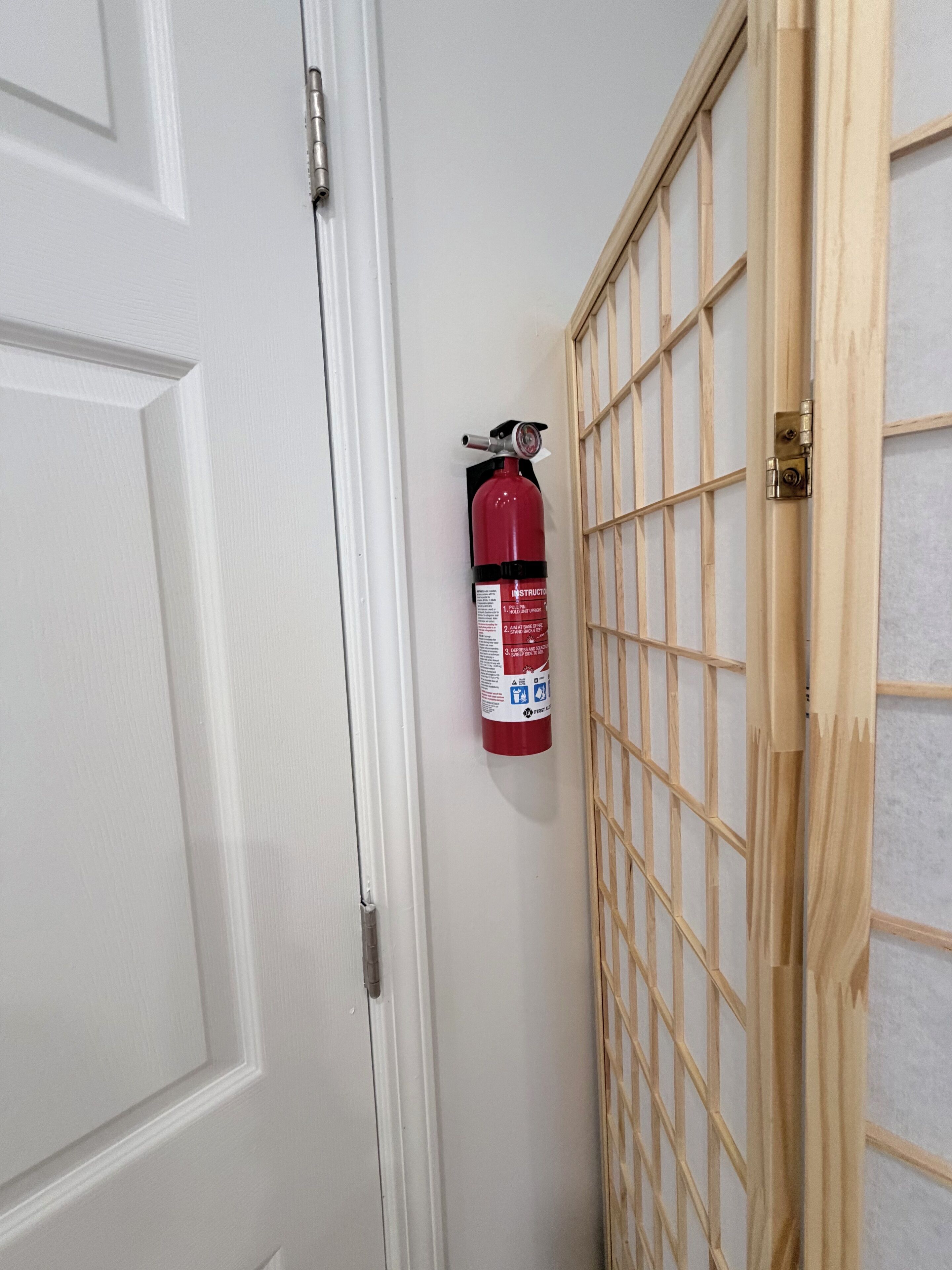 A white door with a fire extinguisher mounted on the wall beside it.