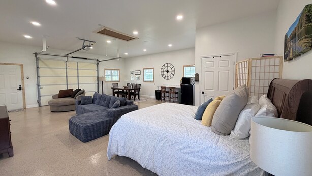A spacious living area with a large bed, a sofa, and a dining table. - Pet-Friendly Mountain Studio - Cozy Stay with Patio & Covered Private Parking (Kingsport)