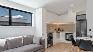 A modern kitchen with white cabinetry, a built-in oven, and a refrigerator.