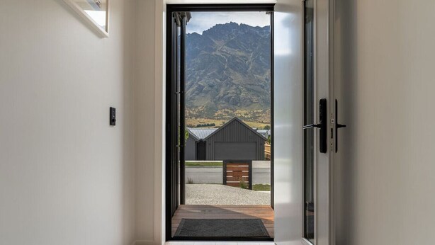 A modern interior with a sliding glass door leading to an outdoor area with a mountain view and a small building. - Executive 3BR 3Queen-Beds Free Unltd WiFi & Garage (Queenstown)